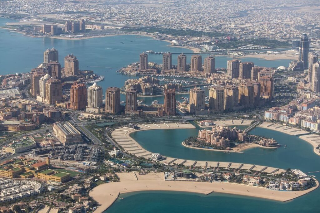 Aerial view of a coastal city featuring modern high-rise buildings, sandy beaches, and blue waterways, showcasing urban development and waterfront lifestyle.