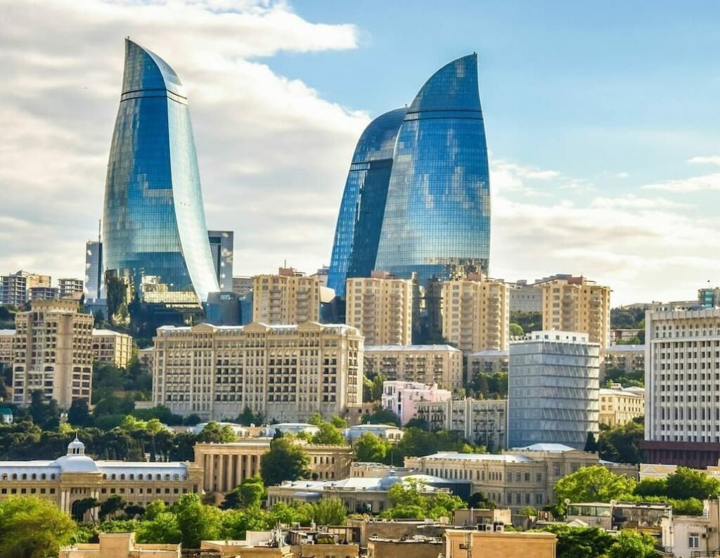 Cityscape of Baku, Azerbaijan featuring the iconic Flame Towers and modern architecture against a blue sky.