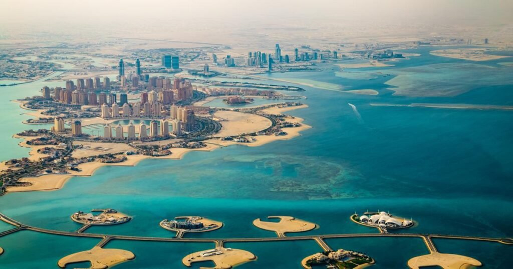 Aerial view of Dubai's coastline showcasing the iconic Palm Jumeirah islands, modern skyscrapers, and the vibrant blue waters of the Arabian Gulf.