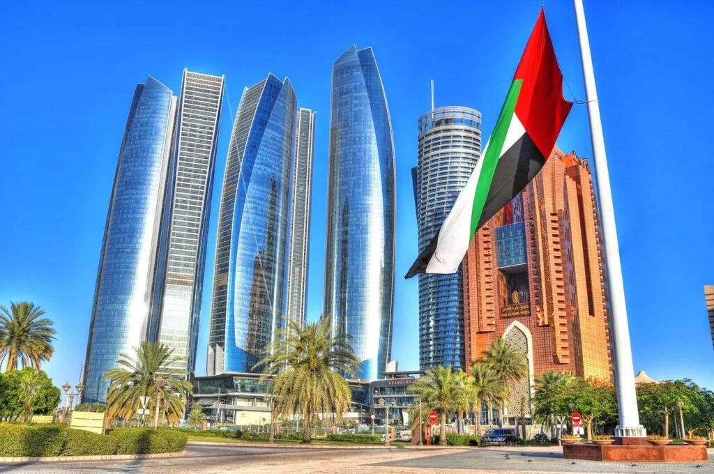 Modern skyscrapers in Abu Dhabi with the UAE flag in the foreground, showcasing the city's architectural advancements and vibrant atmosphere.