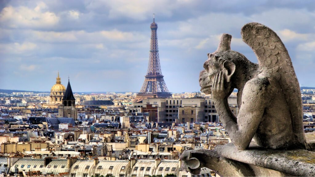 View of Paris skyline featuring the Eiffel Tower in the background, with a gargoyle statue in the foreground. The scene captures a blend of historical architecture and iconic landmarks under a cloudy sky.