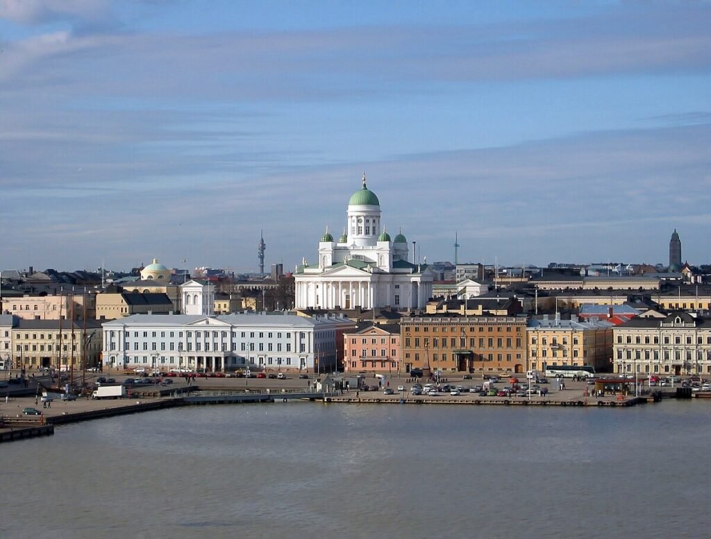 Panoramic view of Helsinki, Finland, showcasing the iconic Helsinki Cathedral with its green dome, surrounded by colorful historic buildings along the waterfront.