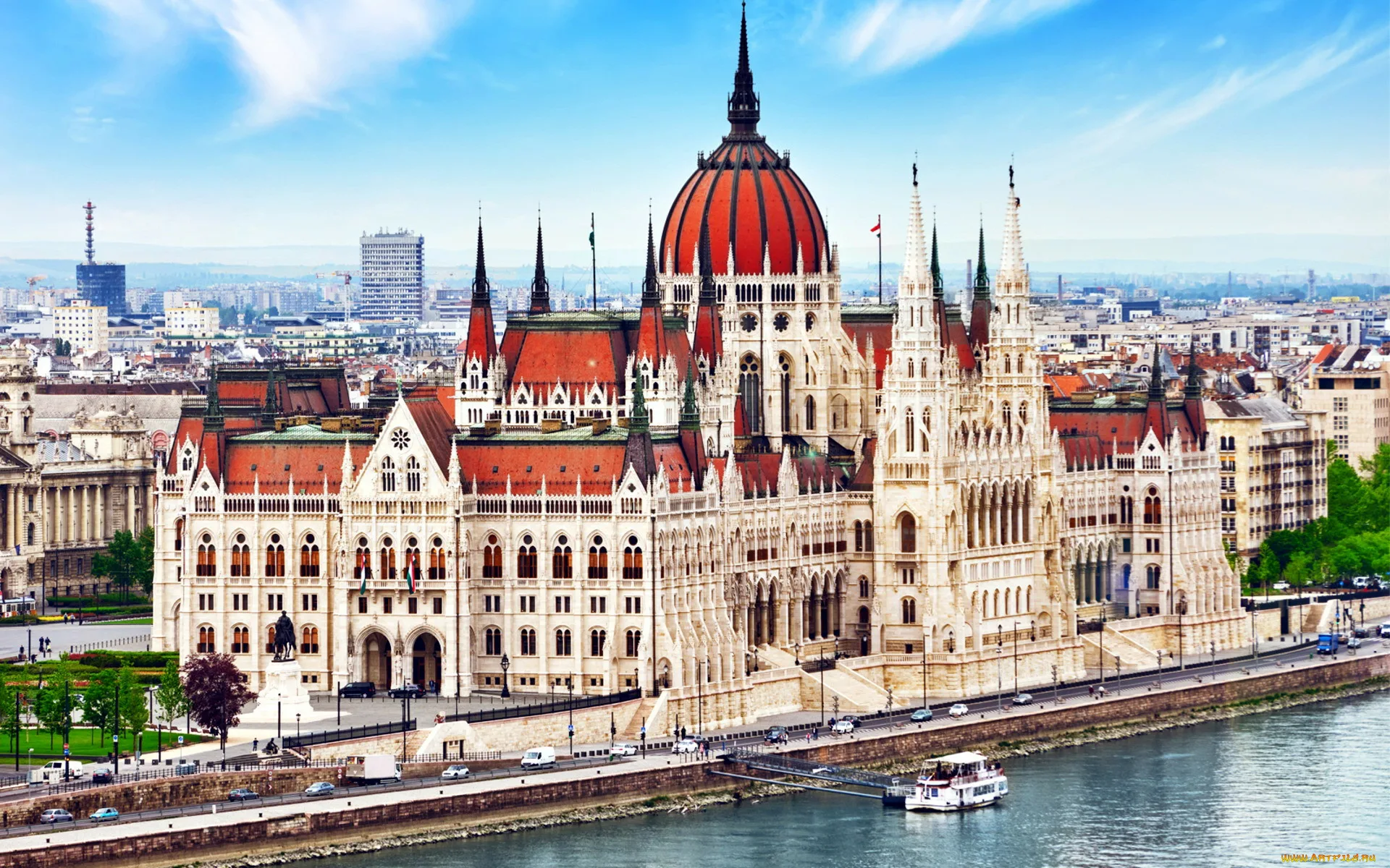 View of the Hungarian Parliament Building in Budapest, showcasing its iconic red dome and neo-Gothic architecture along the Danube River.