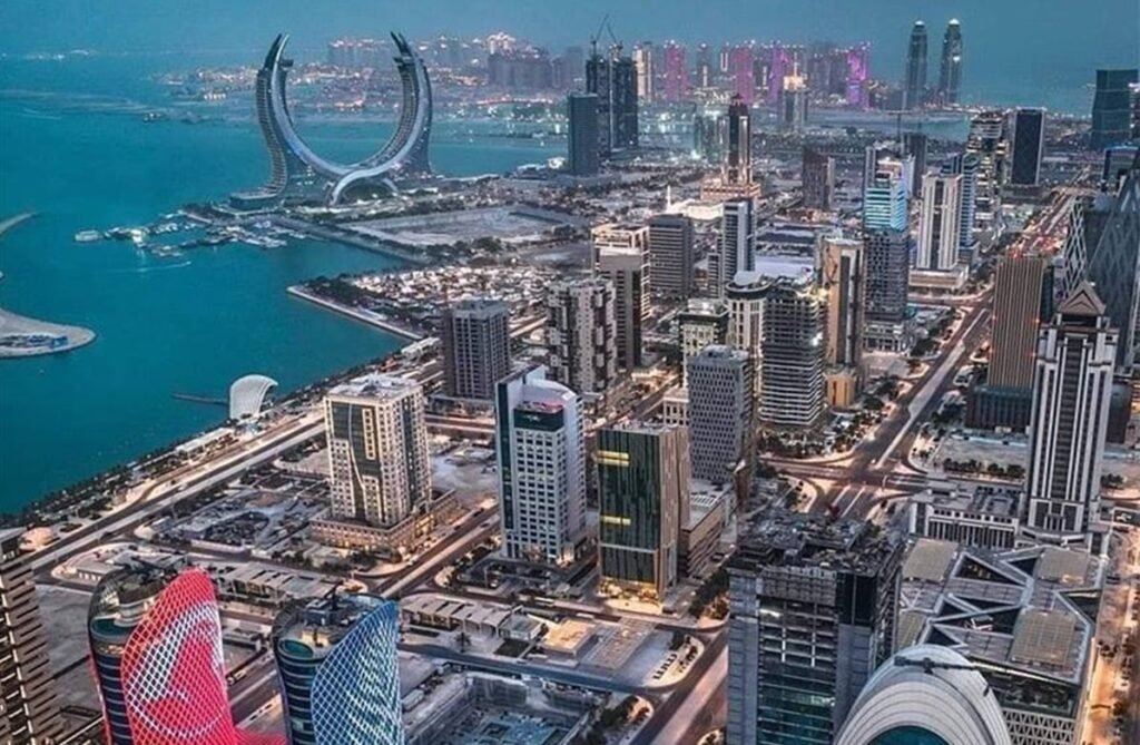 Aerial view of a modern city skyline at dusk, featuring skyscrapers, waterfront developments, and a large circular structure, showcasing urban architecture and vibrant city life.