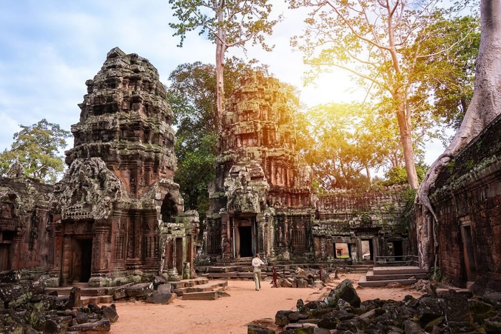 Ancient temple ruins surrounded by lush greenery and sunlight, showcasing intricate stone carvings and historical architecture in Cambodia.