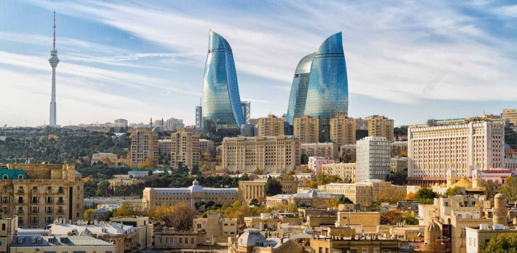 Baku skyline featuring the Flame Towers and TV Tower against a clear blue sky, showcasing modern architecture amidst historical buildings.