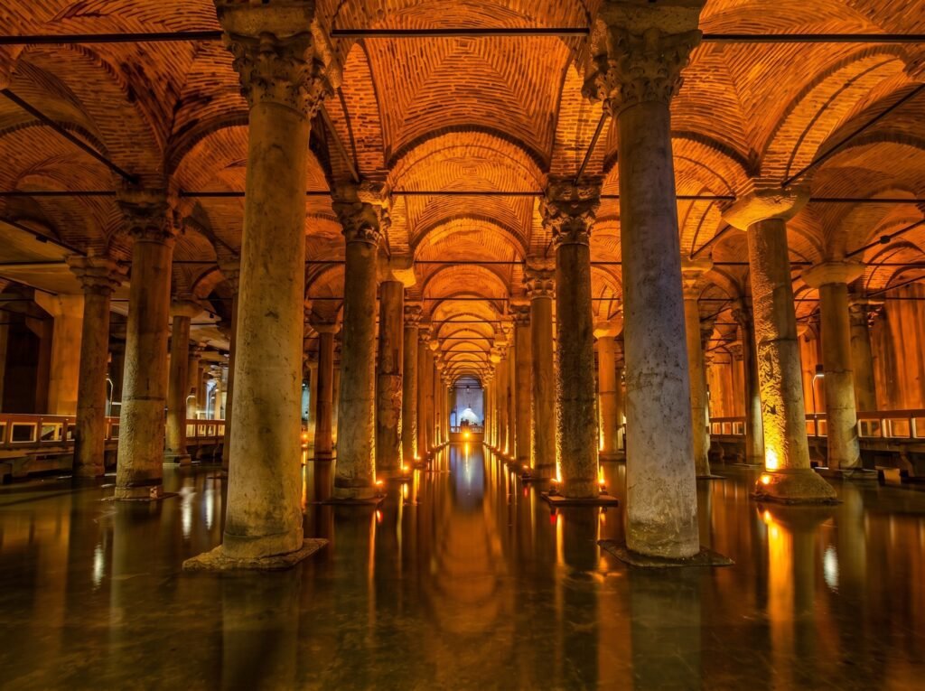 Underground Basilica Cistern in Istanbul, featuring illuminated columns and arches, reflecting water surface, showcasing ancient architecture and historical significance.
