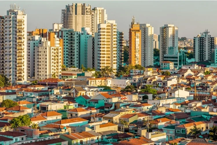 Aerial view of a vibrant urban landscape showcasing a mix of modern high-rise buildings and traditional residential homes with colorful rooftops, highlighting the contrast between city living and suburban areas.