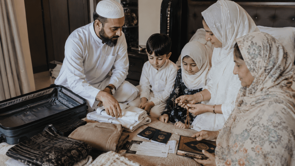 A family preparing for a journey, with a man in traditional attire packing clothes and travel documents alongside two children and two women, all engaged in organizing their belongings on a bed.