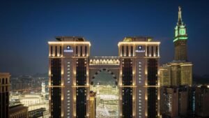 Night view of the Address Hotel in Mecca, showcasing its illuminated architecture and the iconic Abraj Al Bait Clock Tower in the background, highlighting the city's modern skyline and proximity to the Grand Mosque.