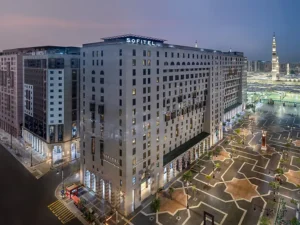 Sofitel hotel in Medina, Saudi Arabia, showcasing modern architecture and elegant design, illuminated at dusk with nearby landmarks visible. Ideal for travelers seeking luxury accommodations near religious sites.