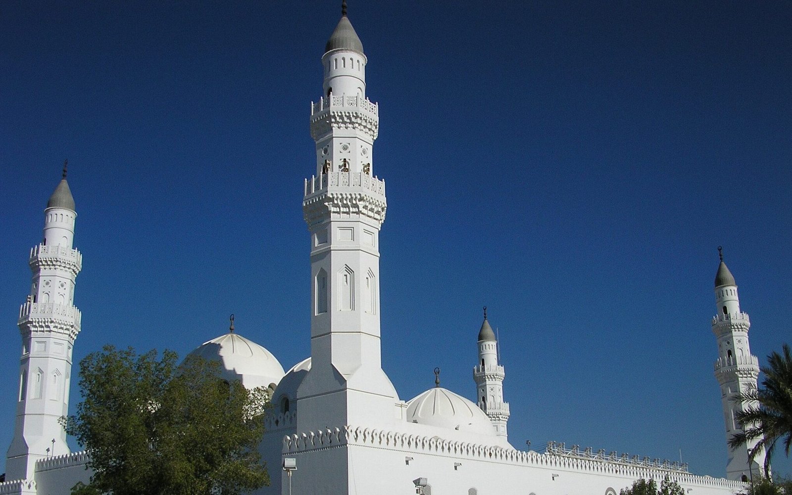 White minarets and domes of Masjid Quba against a blue sky in Madinah