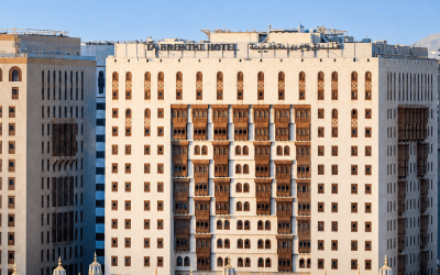 Exterior view of the Abraj Al Bait Clock Tower with decorative domes in the foreground, located in Mecca, Saudi Arabia, showcasing modern architectural design and traditional elements.