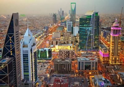 Aerial view of Riyadh, Saudi Arabia, showcasing modern skyscrapers, vibrant city lights, and bustling streets, highlighting the city's rapid urban development and architectural diversity.