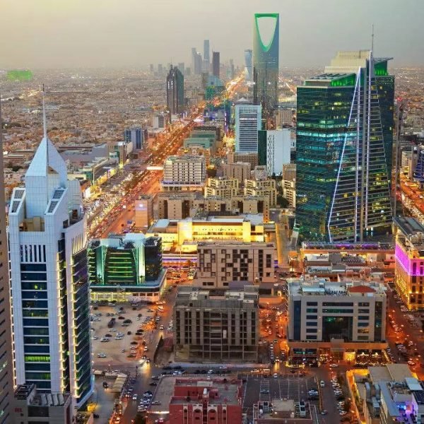 Aerial view of Riyadh, Saudi Arabia, showcasing modern skyscrapers, vibrant city lights, and bustling streets, highlighting the city's rapid urban development and architectural diversity.