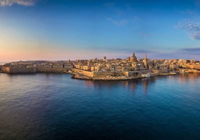 Aerial view of Valletta, Malta, showcasing the historic architecture, waterfront, and vibrant skyline during sunset.