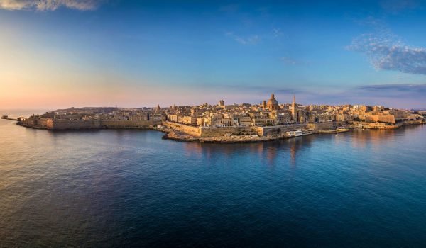 Aerial view of Valletta, Malta, showcasing the historic architecture, waterfront, and vibrant skyline during sunset.