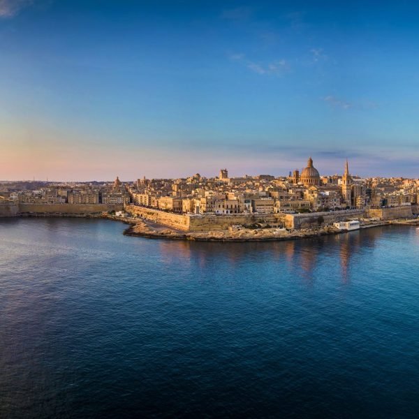 Aerial view of Valletta, Malta, showcasing the historic architecture, waterfront, and vibrant skyline during sunset.