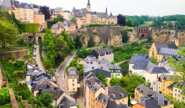 Panoramic view of Luxembourg City showcasing historic architecture, lush greenery, and winding streets, highlighting the blend of modern and medieval elements in the urban landscape.