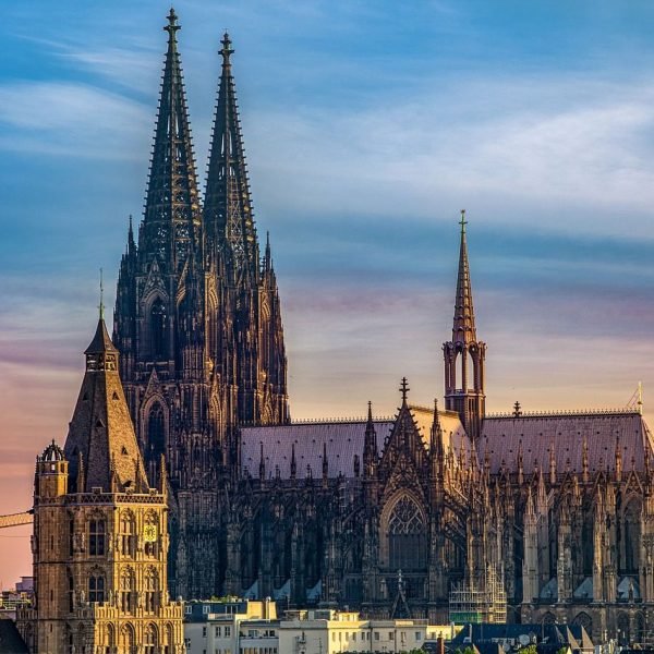 St. Vitus Cathedral in Prague, showcasing its intricate Gothic architecture and towering spires against a colorful sunset sky.