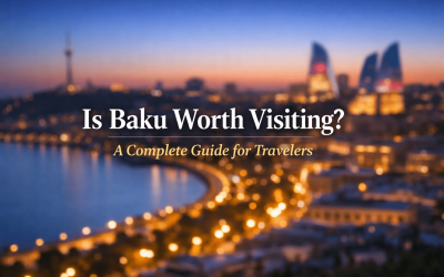 Cityscape of Baku, Azerbaijan at dusk featuring illuminated buildings along the waterfront, with the text overlay "Is Baku Worth Visiting? A Complete Guide for Travelers."